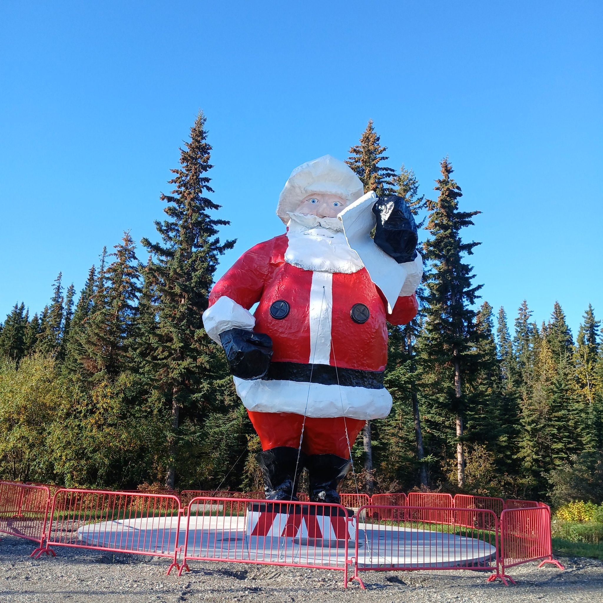 Giant Santa Claus statue standing tall against blue sky at North Pole, Alaska