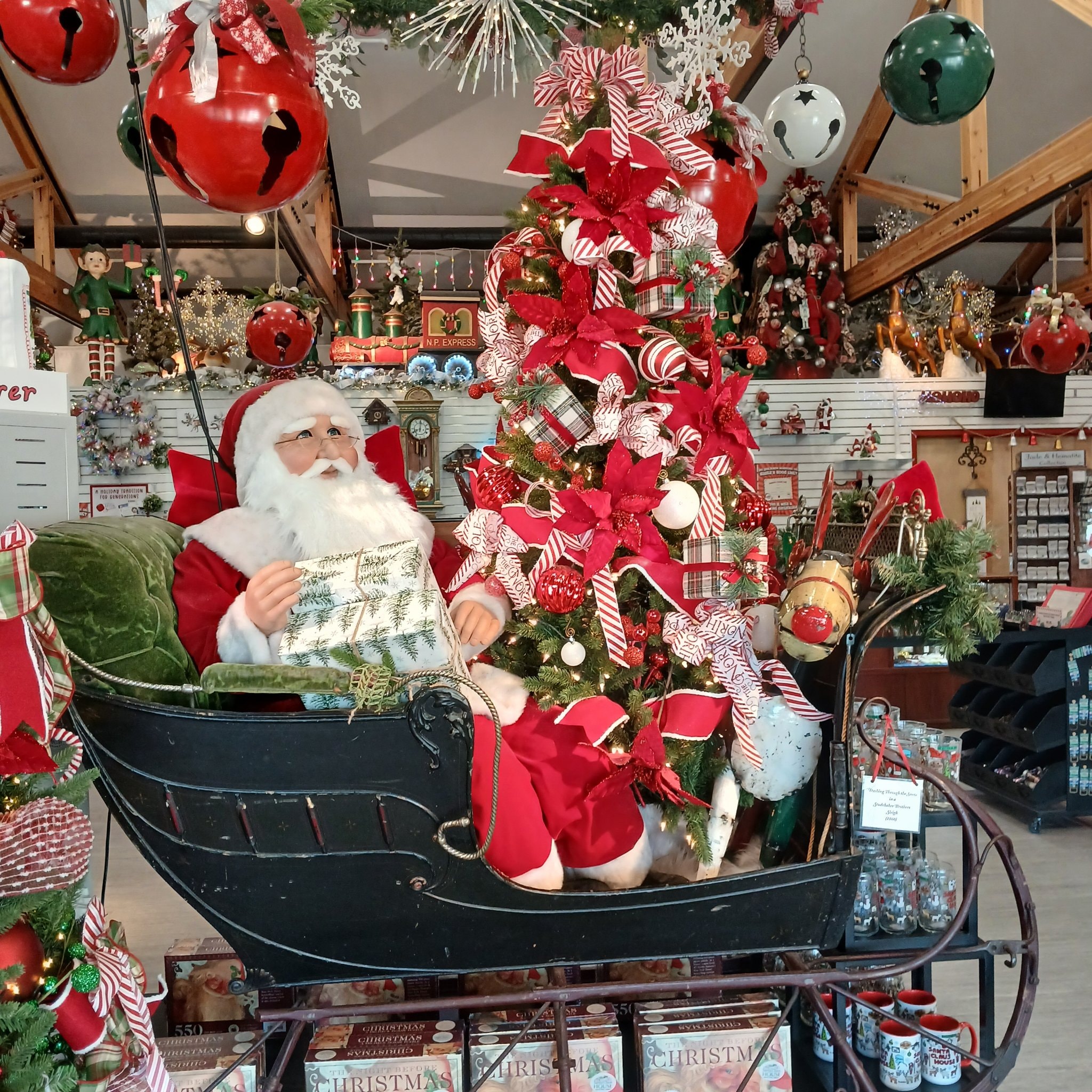Santa in his sleigh surrounded by Christmas trees and ornaments inside the North Pole shop