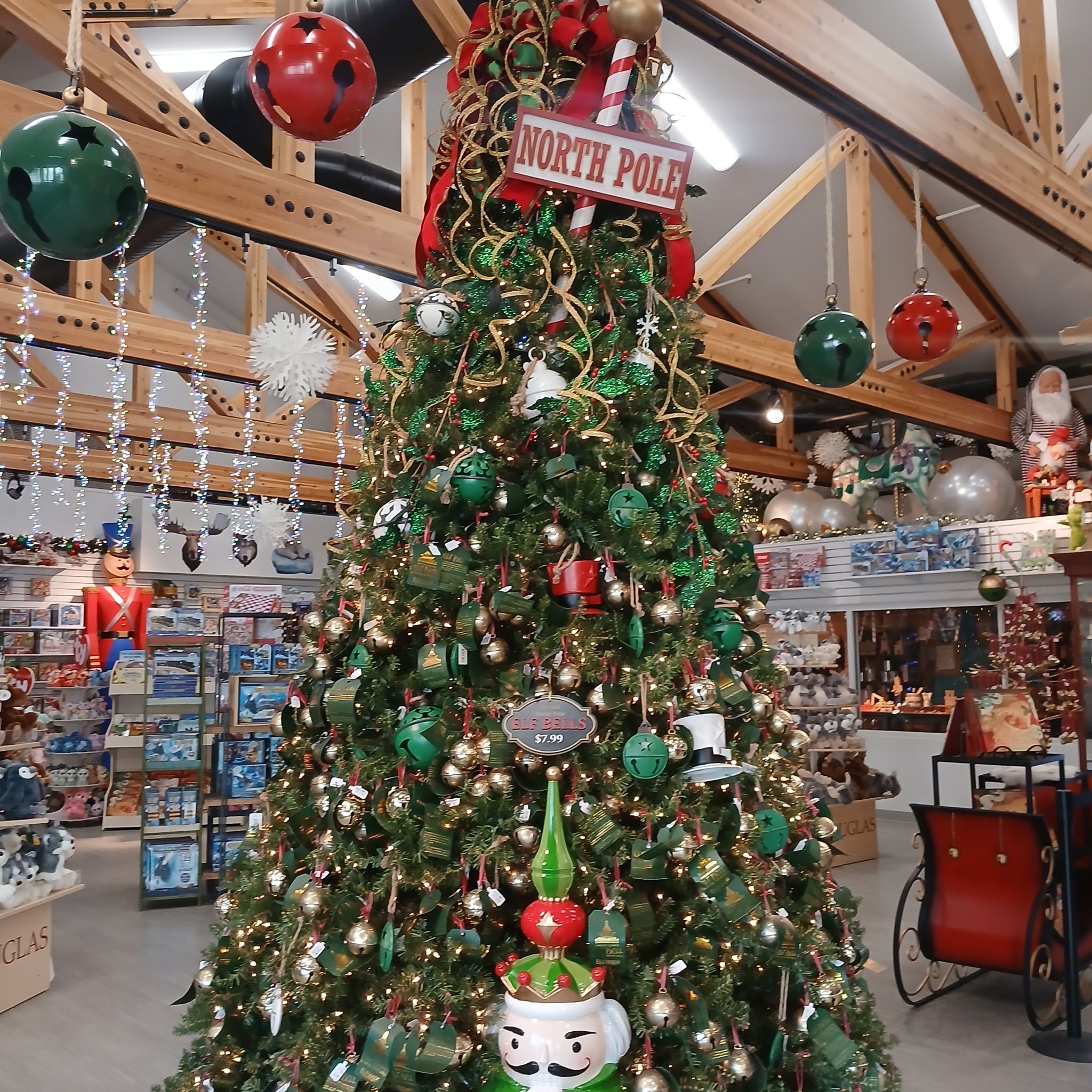 Tall Christmas tree with North Pole sign and jingle bell ornaments