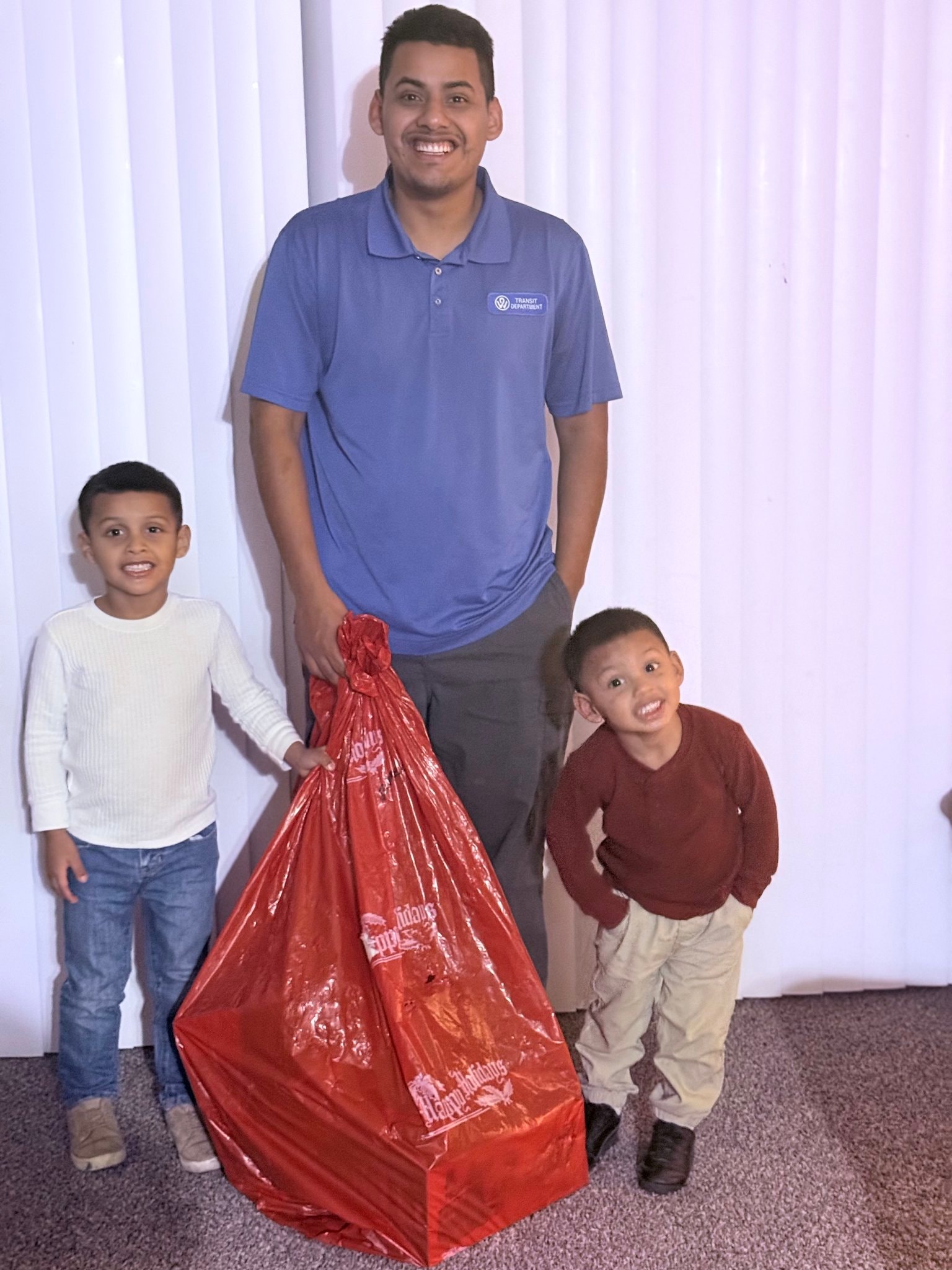 Adult and two children with a large holiday gift bag at community event