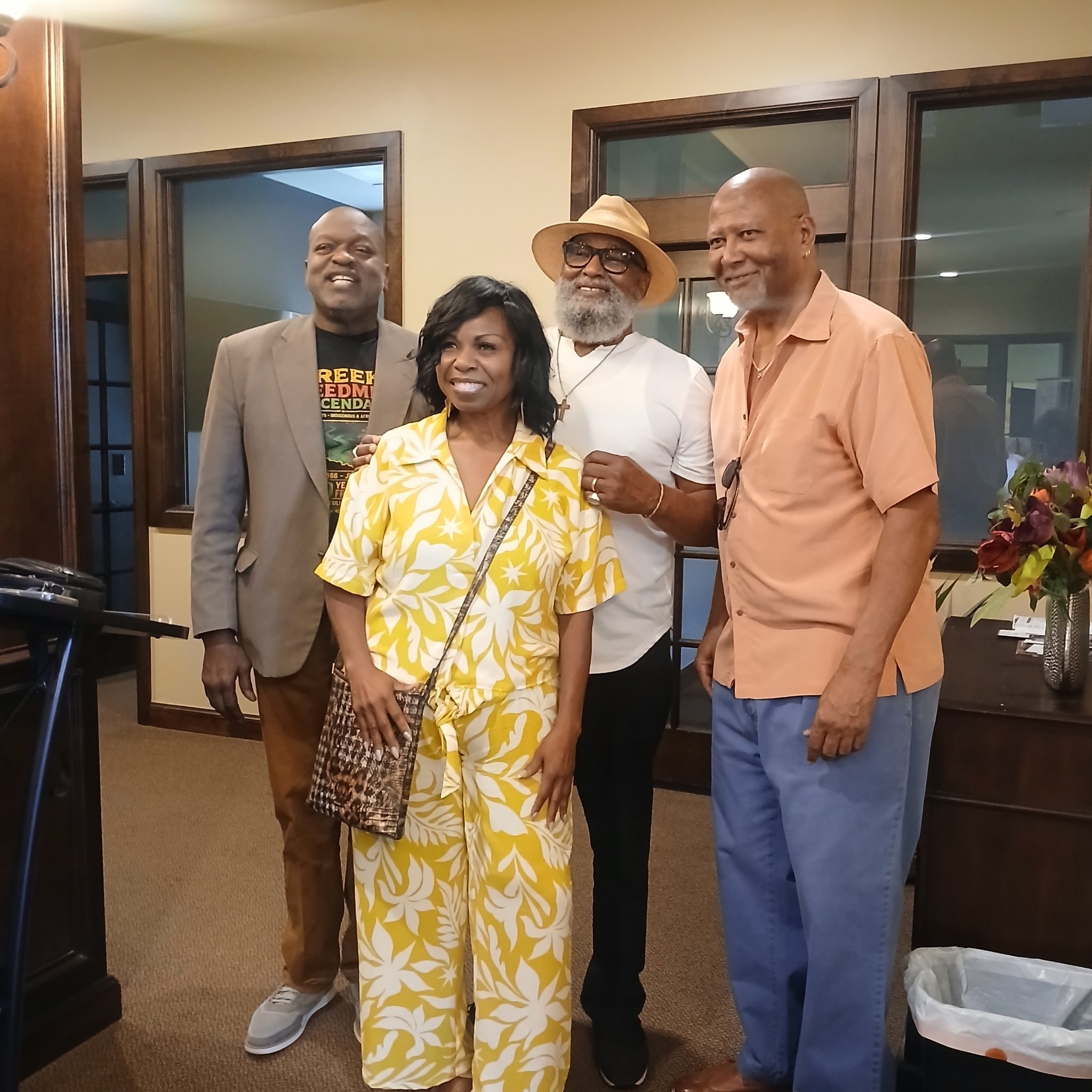 Four people posing together indoors at community event