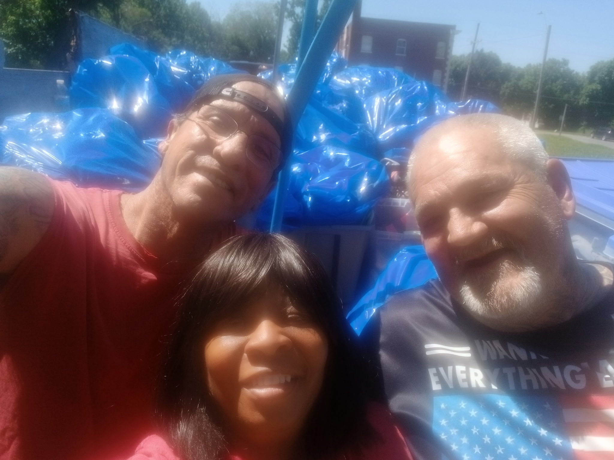 Three volunteers taking a selfie outdoors with blue donation bags